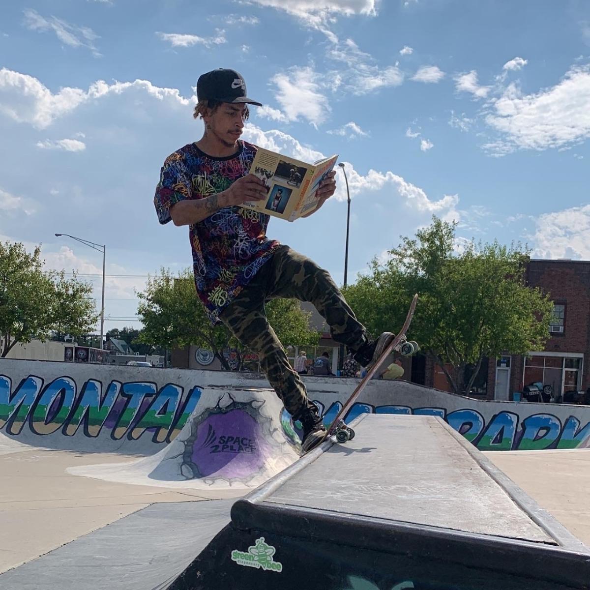 A skateboarder performs a trick while reading a book.